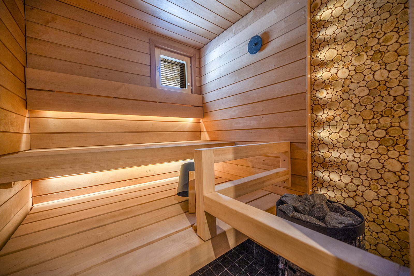 Valoisa sauna LED-lautevalaistuksella ja puukiekko-seinällä